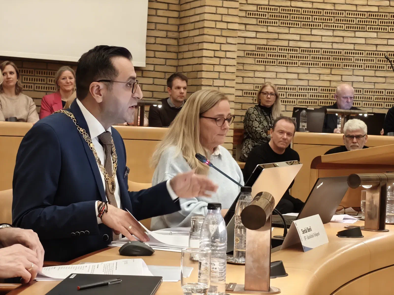 Serdal Benli gestikulerer ved sin plads i byrådssalen