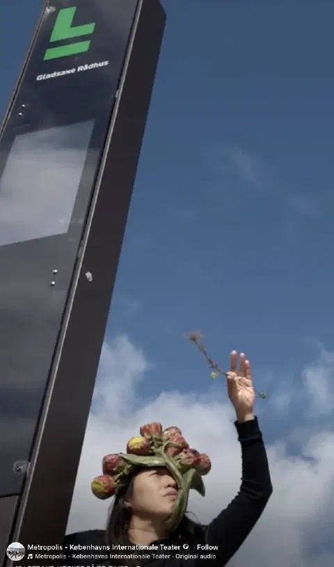 Performer med blomsterhat og en gren ved Gladsaxe Rådhus Station
