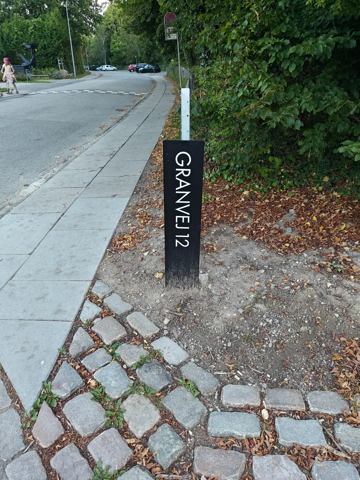 Sort skilt med teksten Granvej 12 ved indkørslen til bostedet