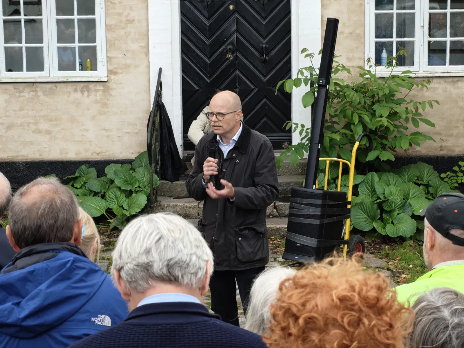 Taleren svarer på spørgsmål foran hovedbygningens facade