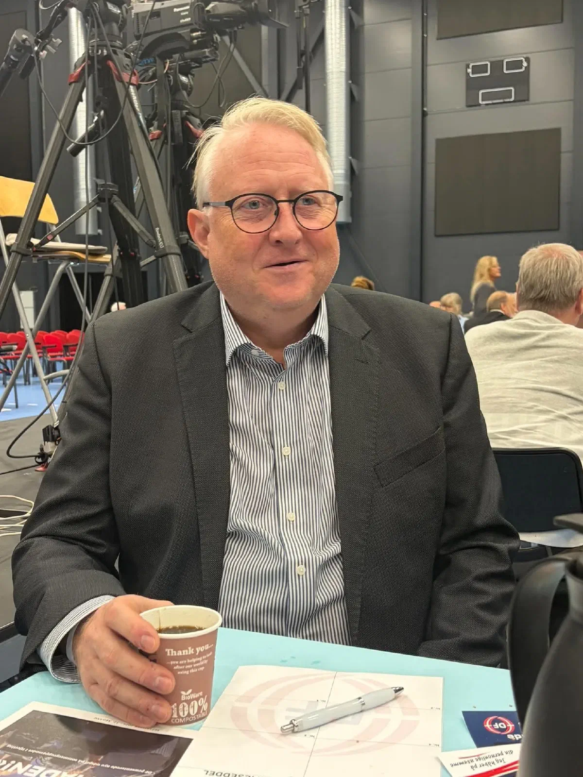 Kristian Tørning ved et bord i salen med en kop kaffe og mødepapirer