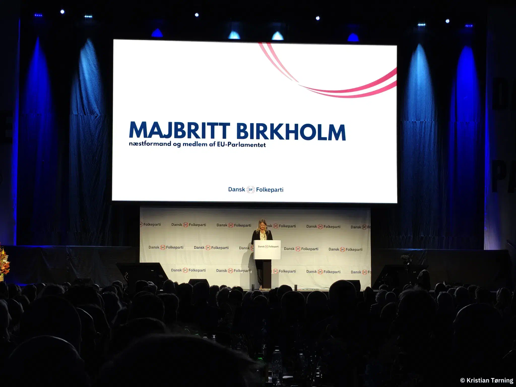Majbritt Birkholm på talerstolen under en skærm med hendes navn