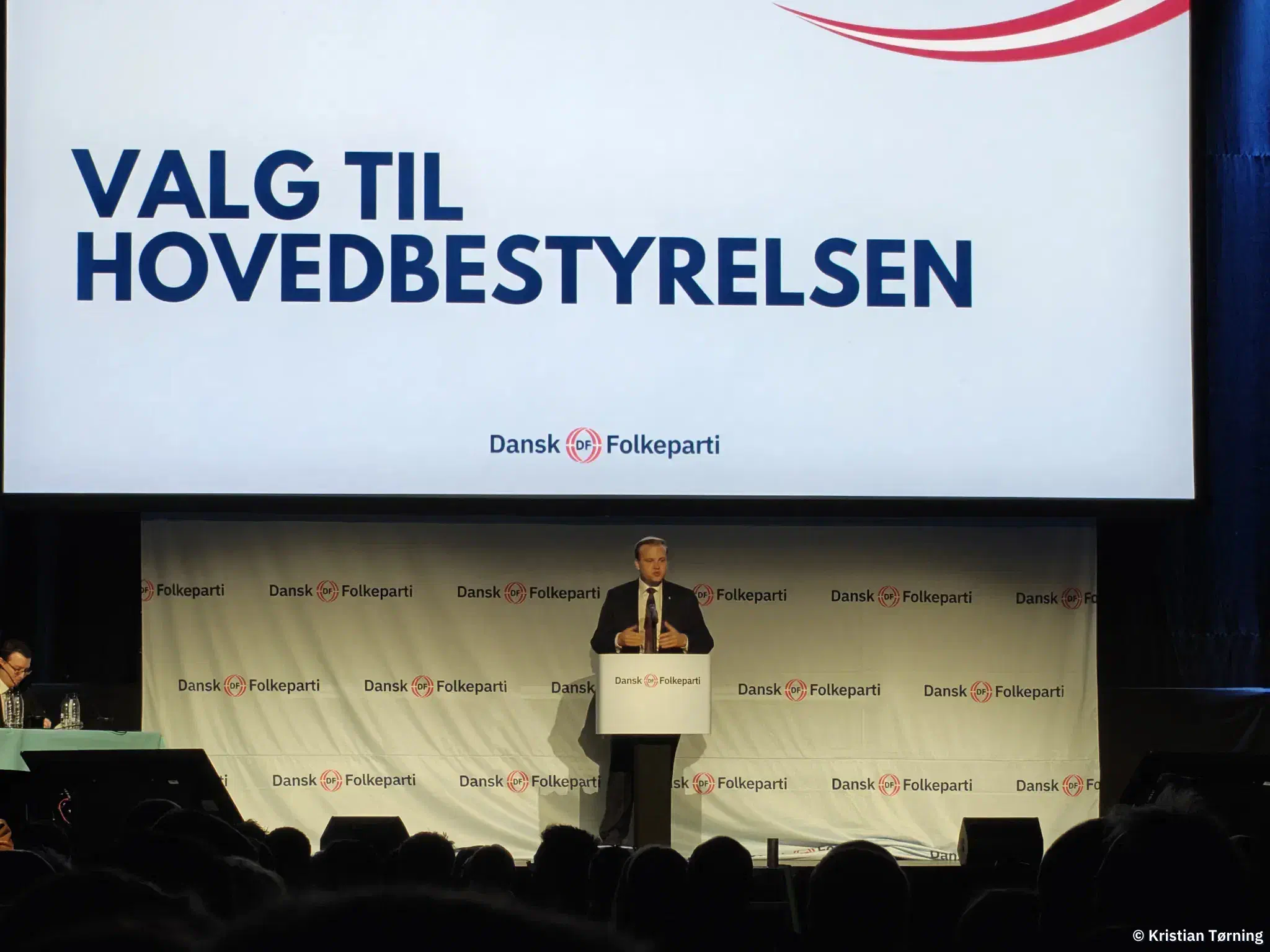 En taler ved talerstolen under en skærm med teksten Valg til hovedbestyrelsen