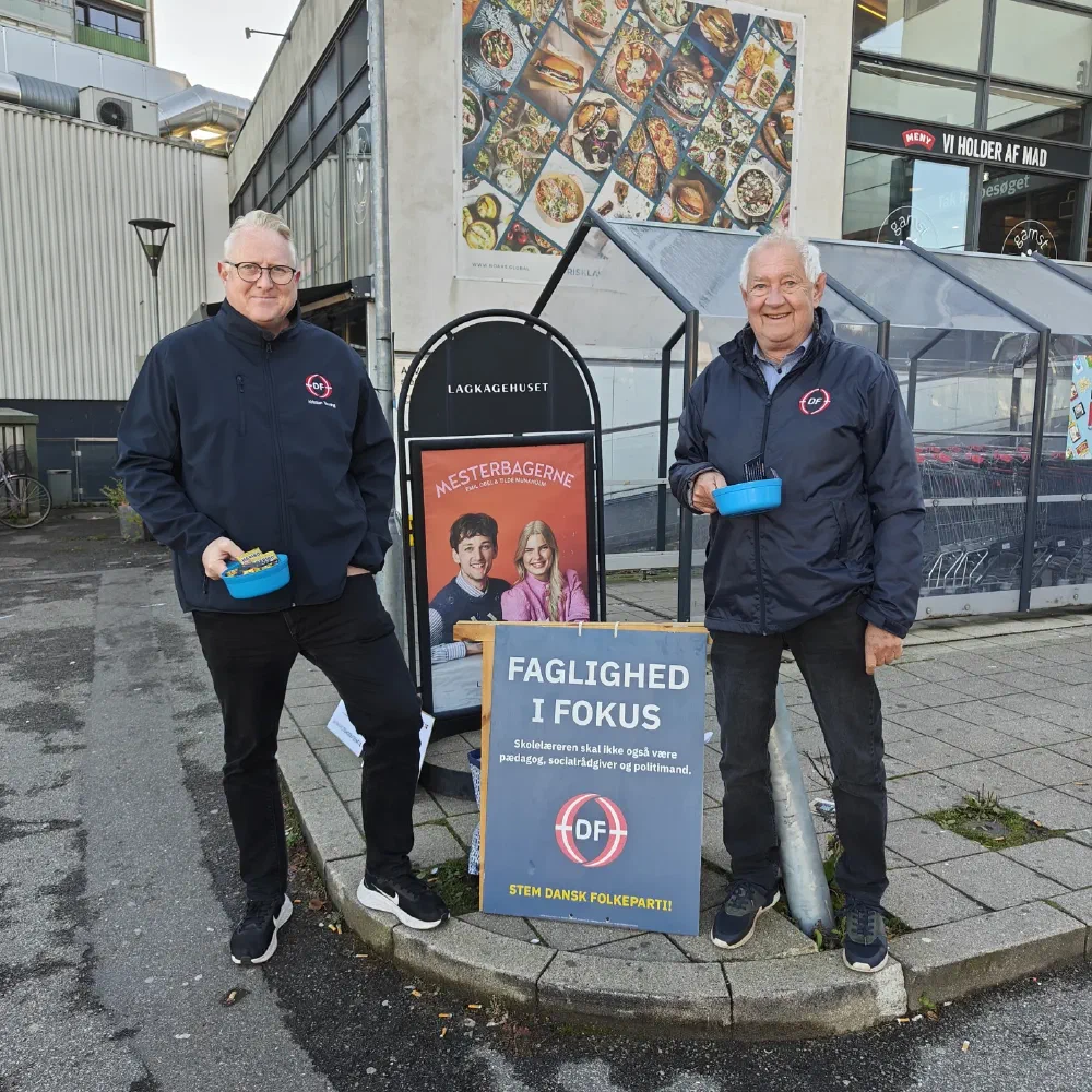 Kristian Tørning og en partikollega med slikskåle og DF-skilt foran butikker