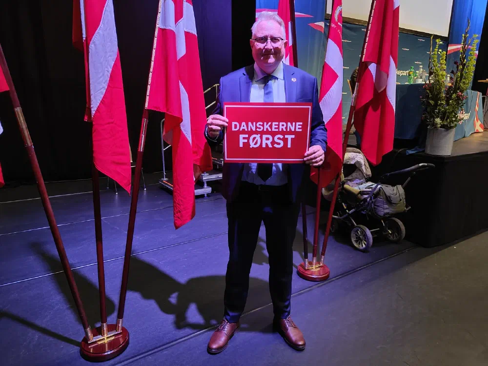 Kristian Tørning holder et skilt med teksten Danskerne Først blandt Dannebrogsflag