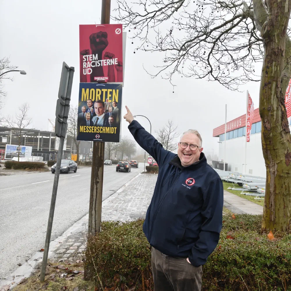 Kristian Tørning peger på Enhedslistens valgplakat ved en trafikeret vej